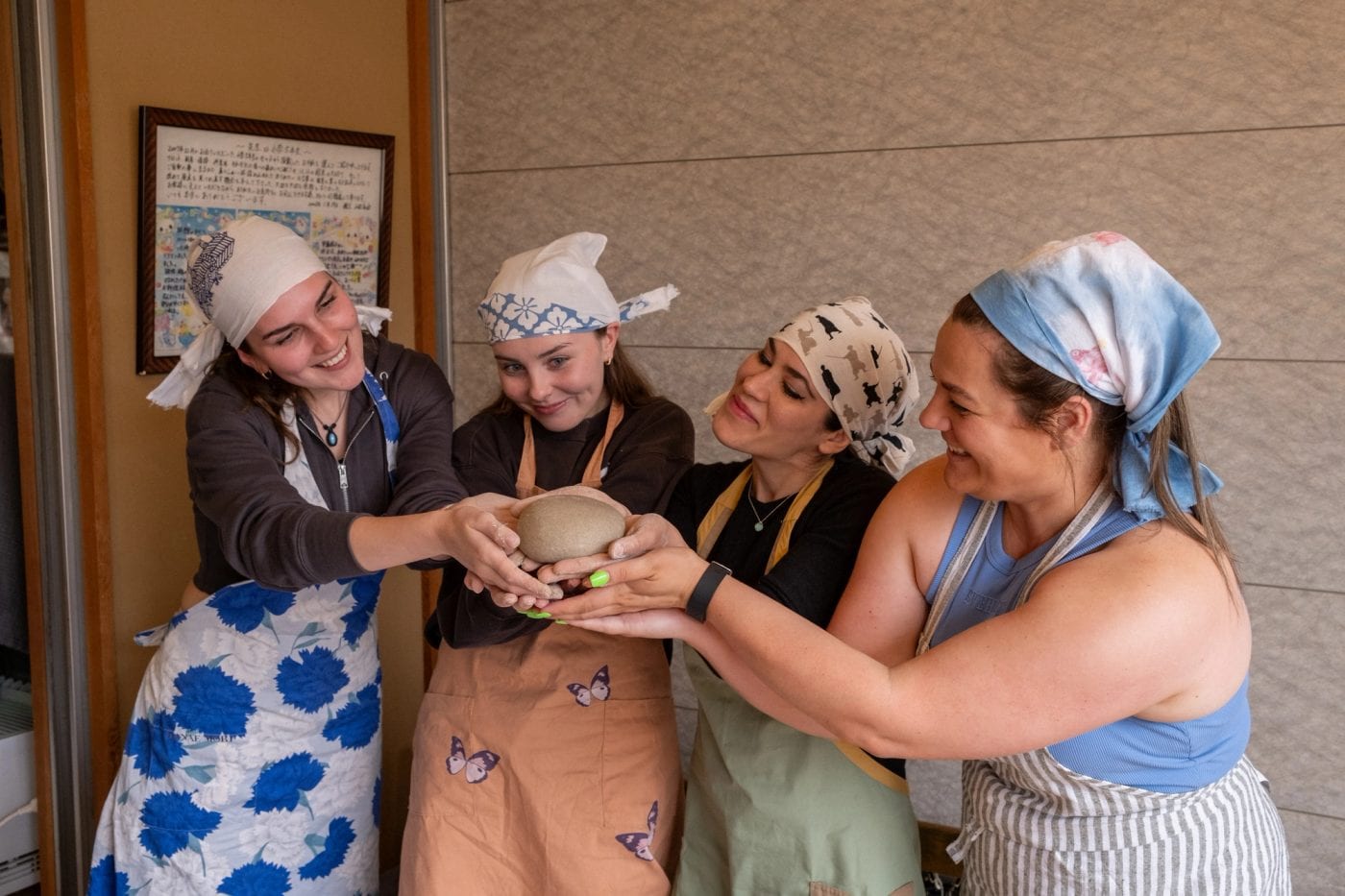 Four friends laughing together at a pottery class in Japan