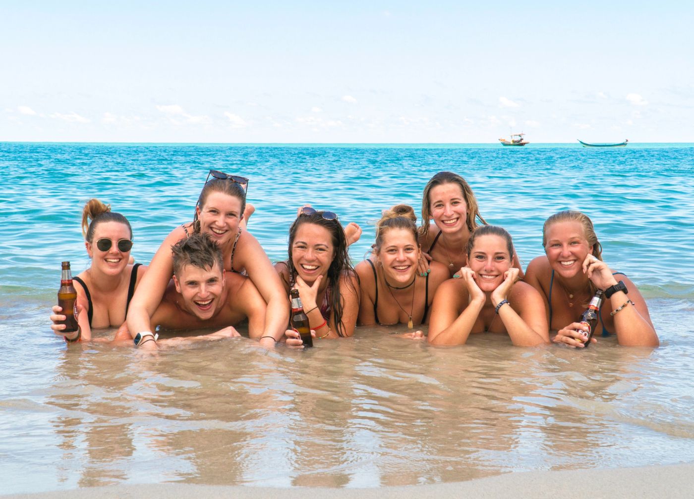 A big group of Wanderlust travellers laughing together in the sea in Thailand
