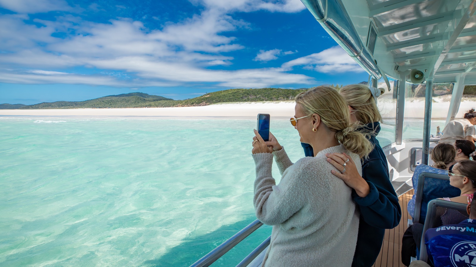 Two friends photographing Whitehaven Beach from the boat deck in the Whitsundays